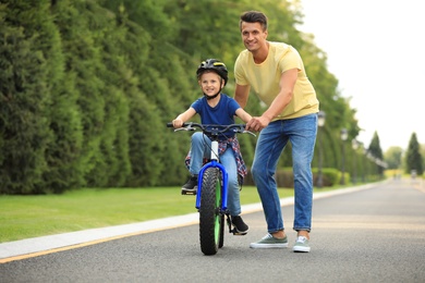 Dad teaching son to ride bicycle outdoors