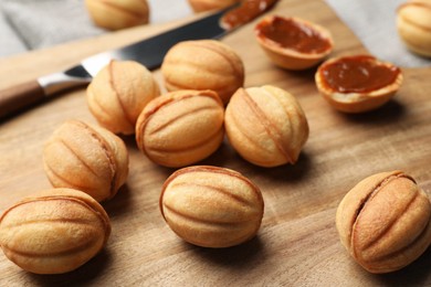 Photo of Homemade walnut shaped cookies with boiled condensed milk on wooden board, closeup
