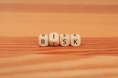 Photo of Cubes with word Risk on wooden table, closeup