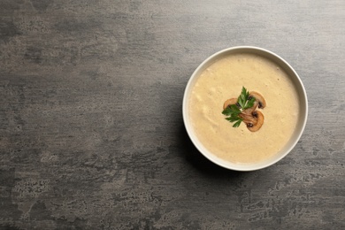 Photo of Bowl of fresh homemade mushroom soup on gray background, top view with space for text