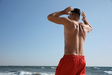 Man with attractive body on beach, back view