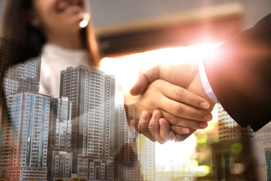 Double exposure of cityscape and business people shaking hands in office, closeup. Team work 