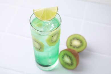 Photo of Glass of refreshing drink and cut kiwi on white table, closeup