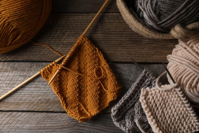 Photo of Soft knitting, needles and colorful yarns on wooden table, flat lay