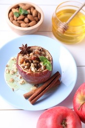 Photo of Tasty baked apple with nuts, honey, spices and mint on white wooden table, above view