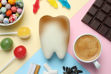 Photo of Decayed tooth model and harmful for enamel products on color background, flat lay