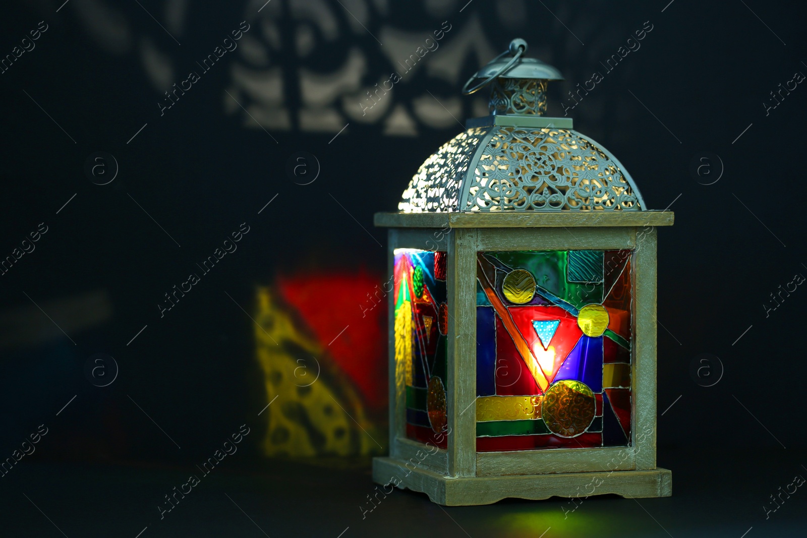 Photo of Decorative Arabic lantern on table against dark background. Space for text