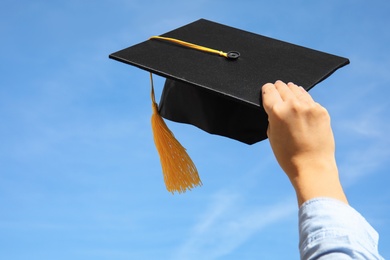 Photo of Student with graduation hat and blue sky on background, closeup