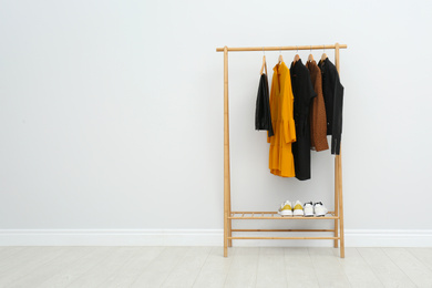 Wooden rack with stylish clothes in room. Space for text