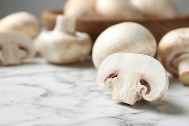 Photo of Fresh champignon mushrooms on marble table, closeup. Space for text