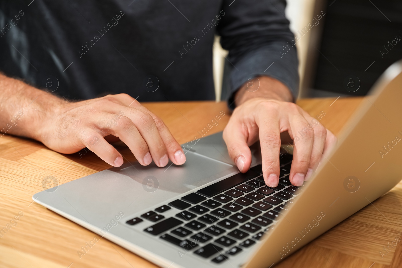 Photo of Man using laptop for search at wooden table, closeup