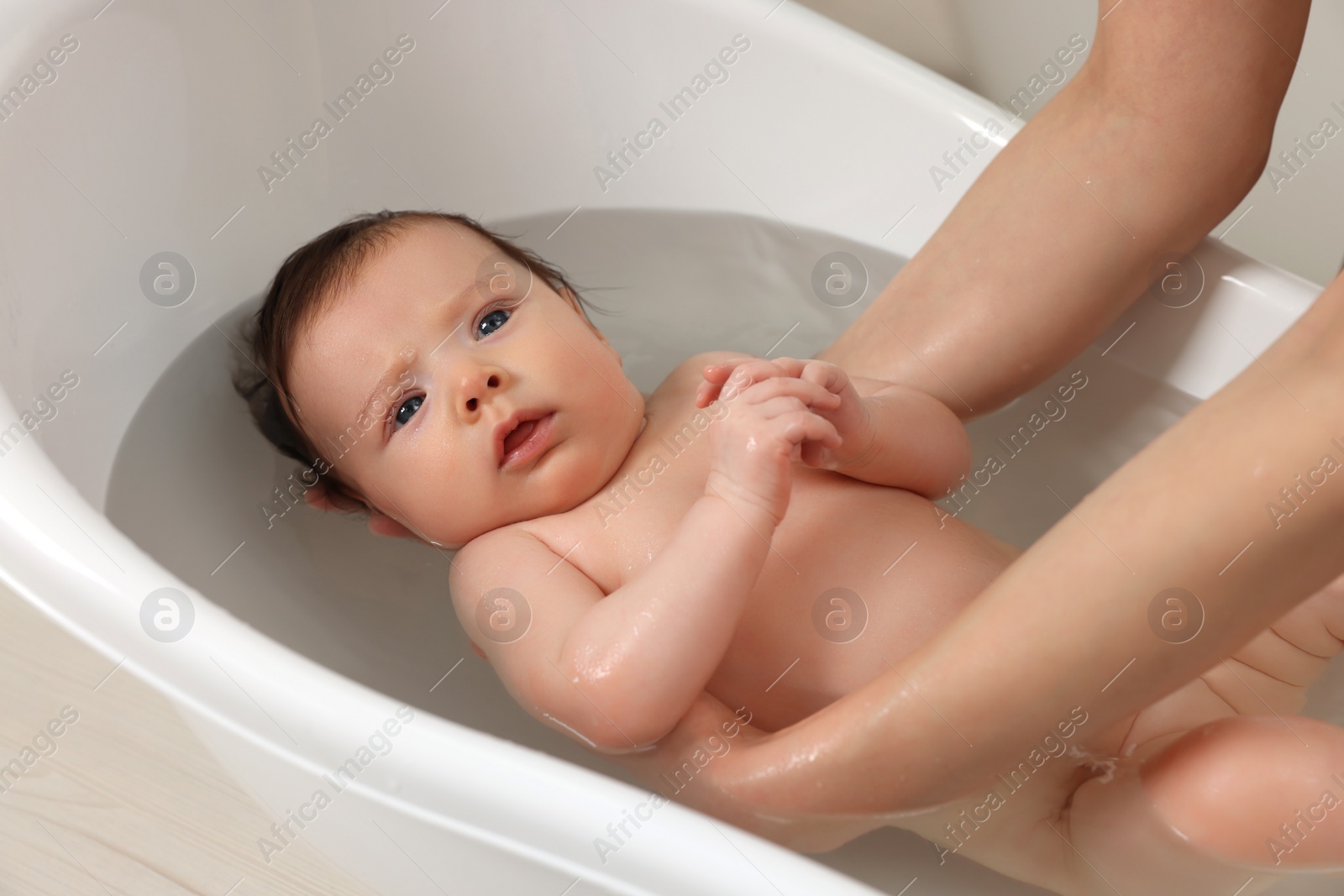 Photo of Mother bathing her little baby in bathtub, closeup