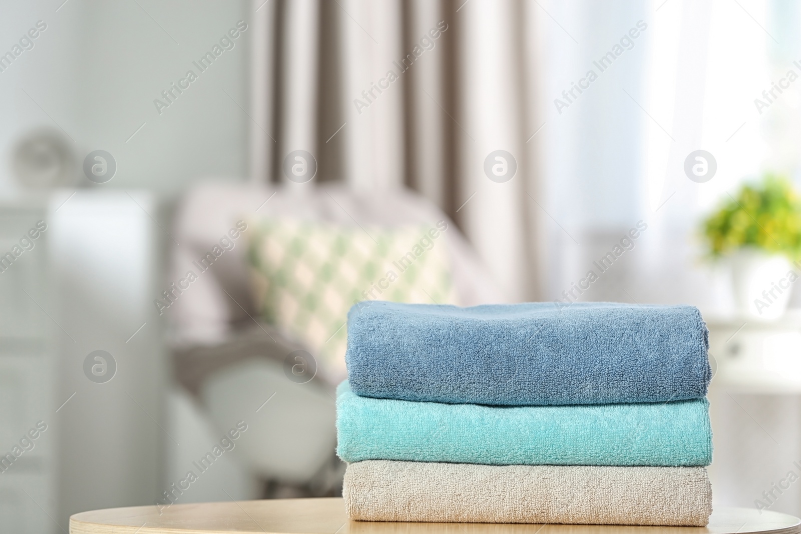 Photo of Stack of folded clean soft towels on table indoors. Space for text