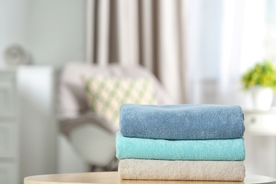 Stack of folded clean soft towels on table indoors. Space for text