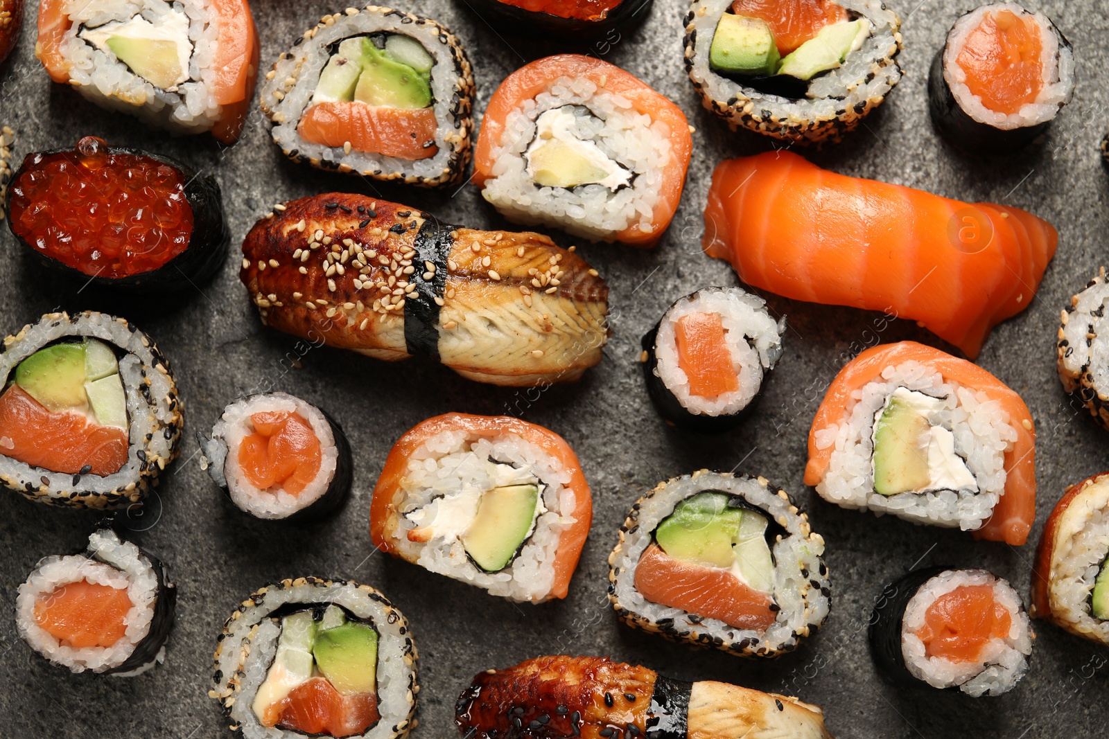 Photo of Different tasty sushi rolls on grey table, flat lay