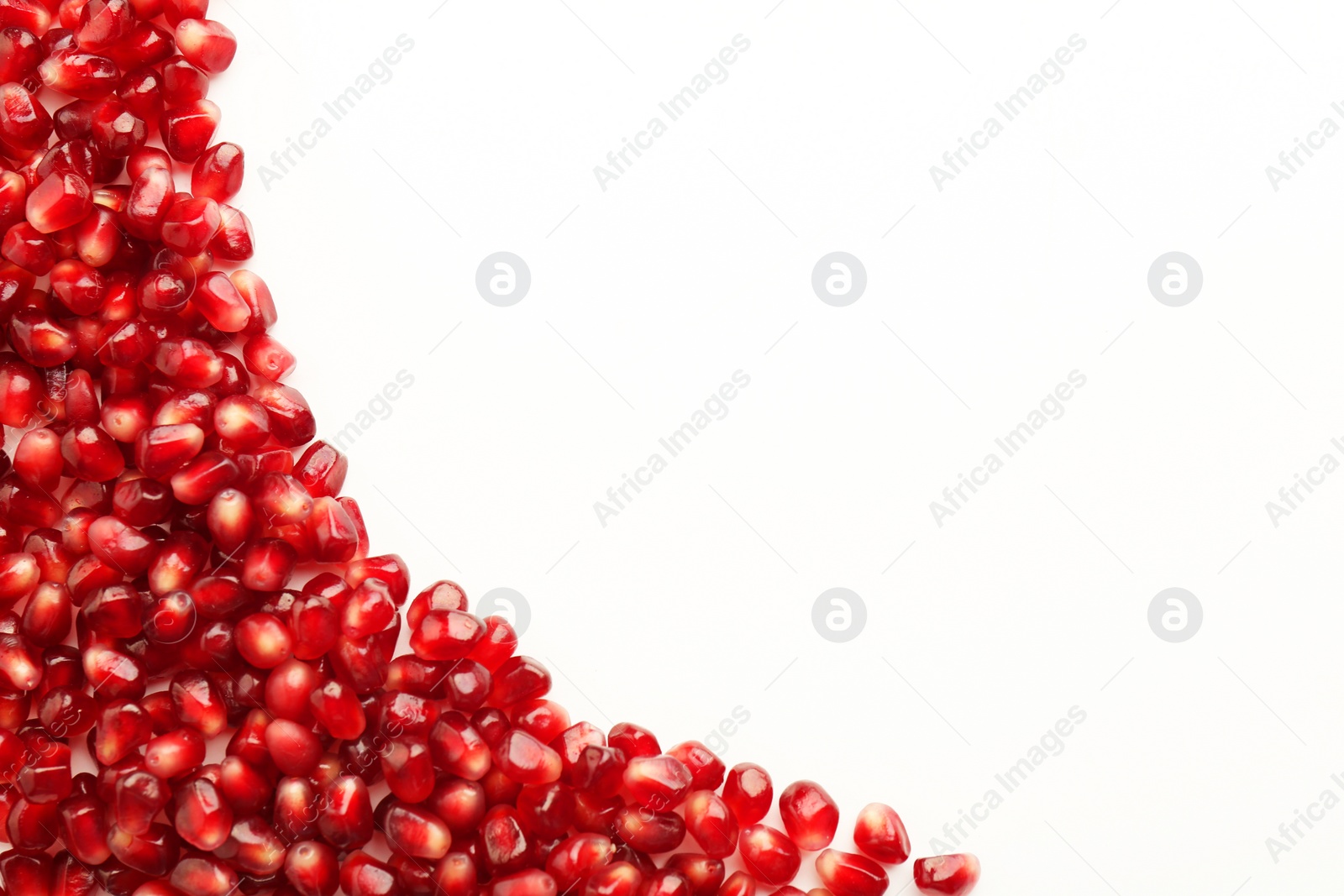 Photo of Many ripe juicy pomegranate grains on white background, flat lay. Space for text