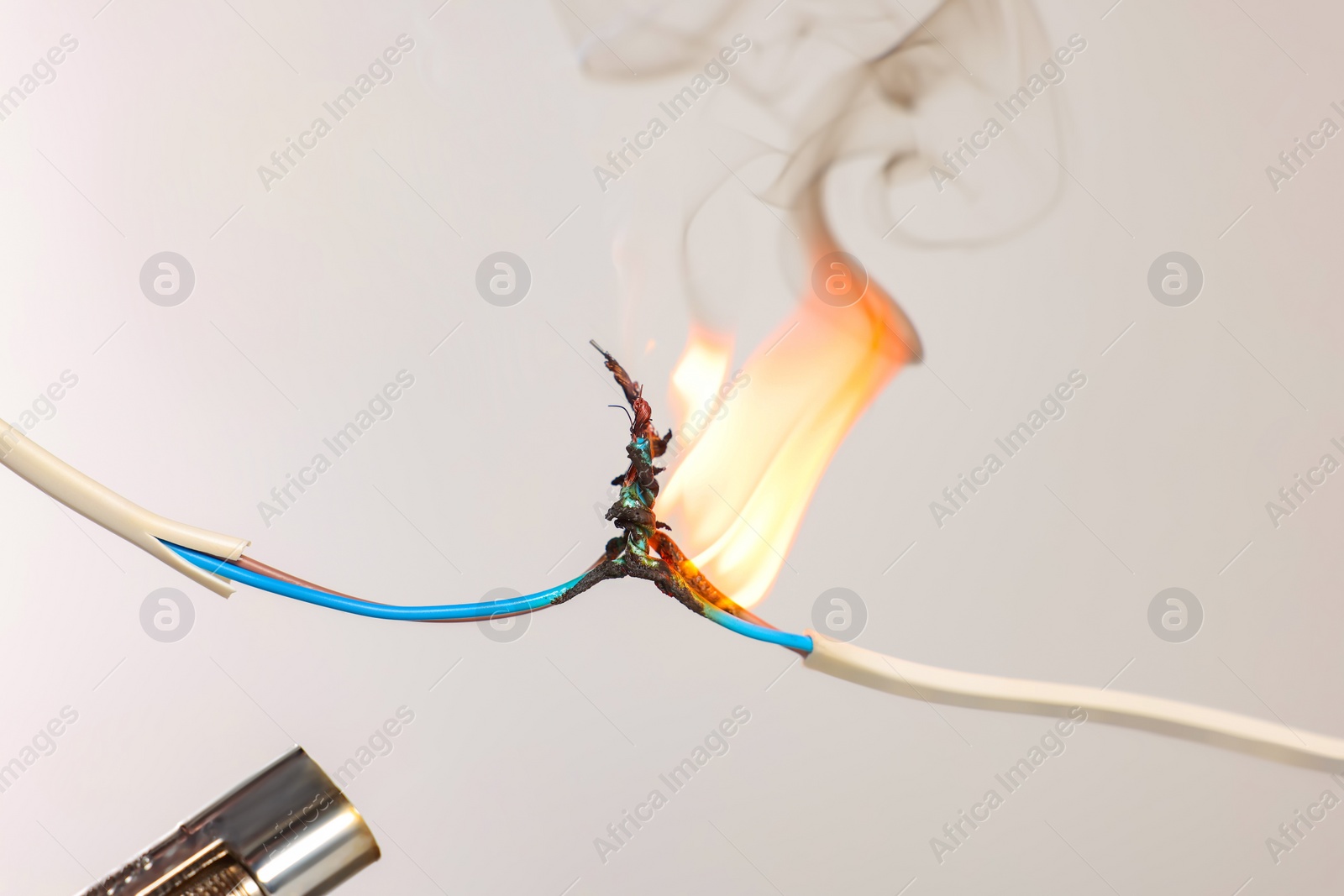 Photo of Inflamed white wire on grey background, closeup. Electrical short circuit