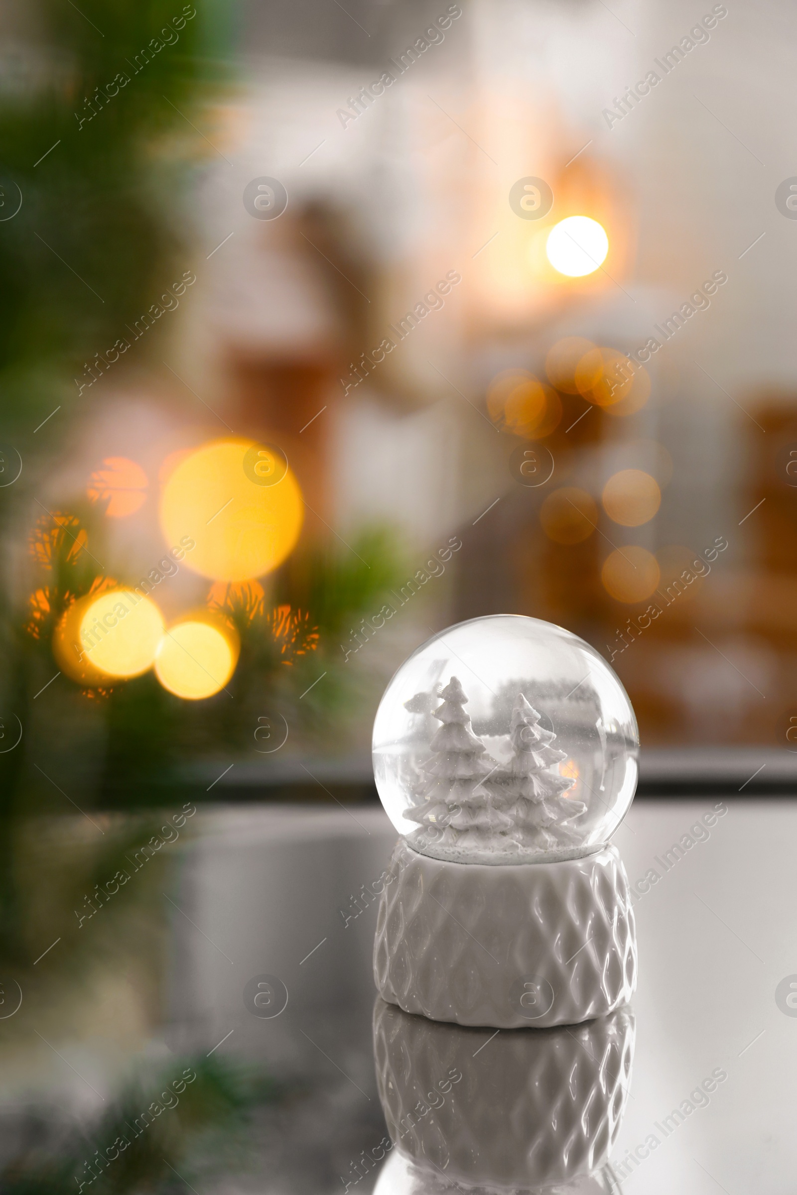 Photo of Decorative Christmas snow globe on mirror surface