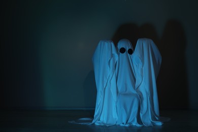 Photo of Creepy ghost. Woman covered with sheet in color light, space for text