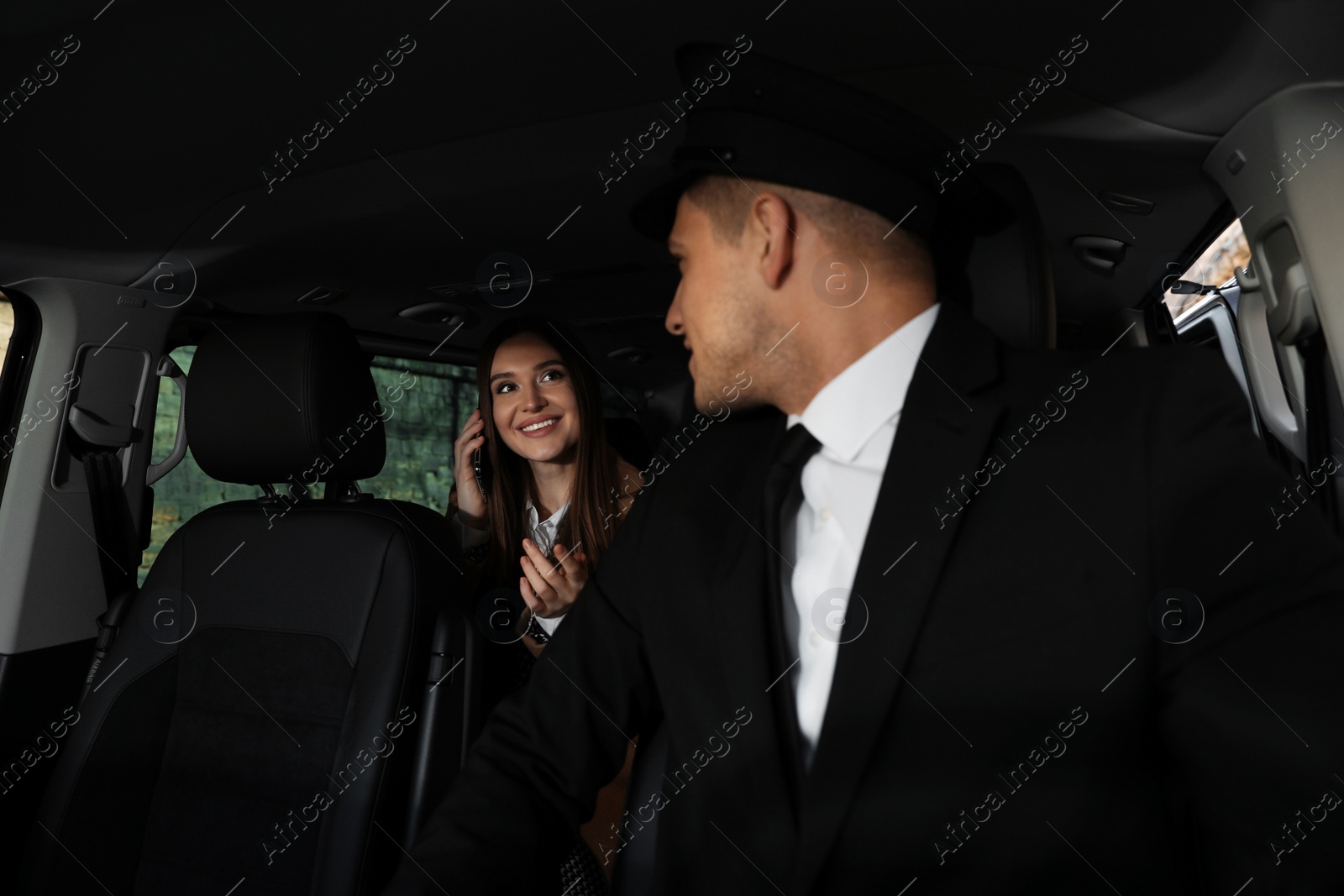 Photo of Professional driver and businesswoman in luxury car. Chauffeur service