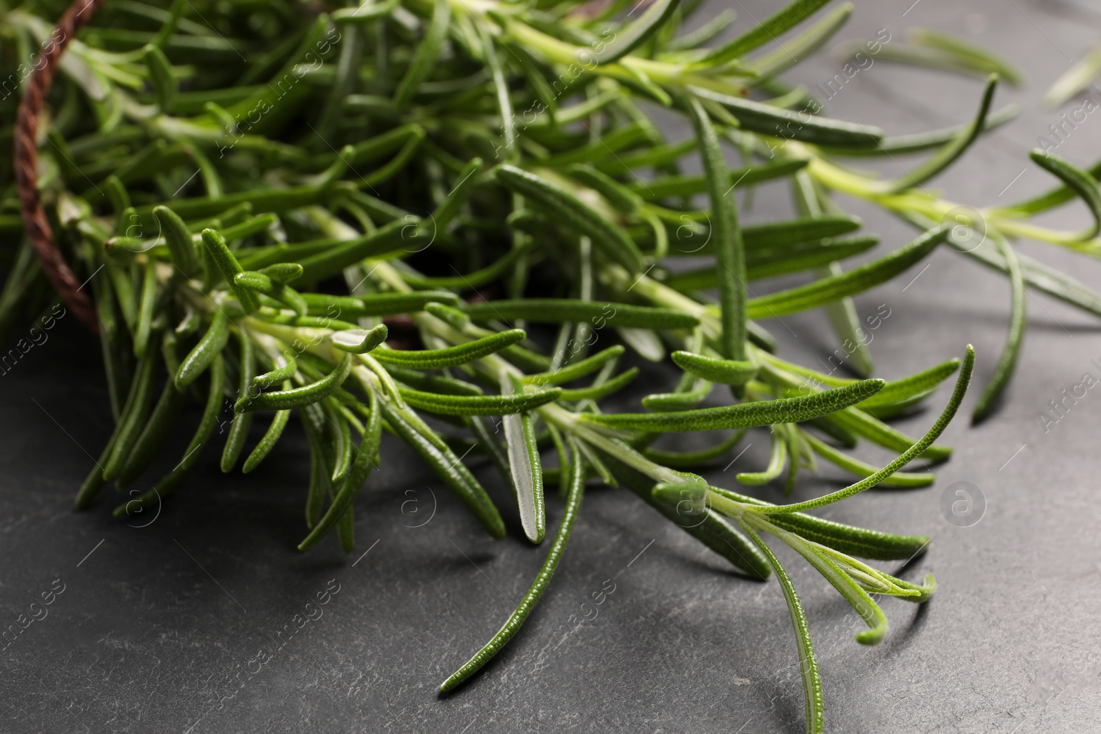 Photo of Sprigs of fresh rosemary on black table, closeup