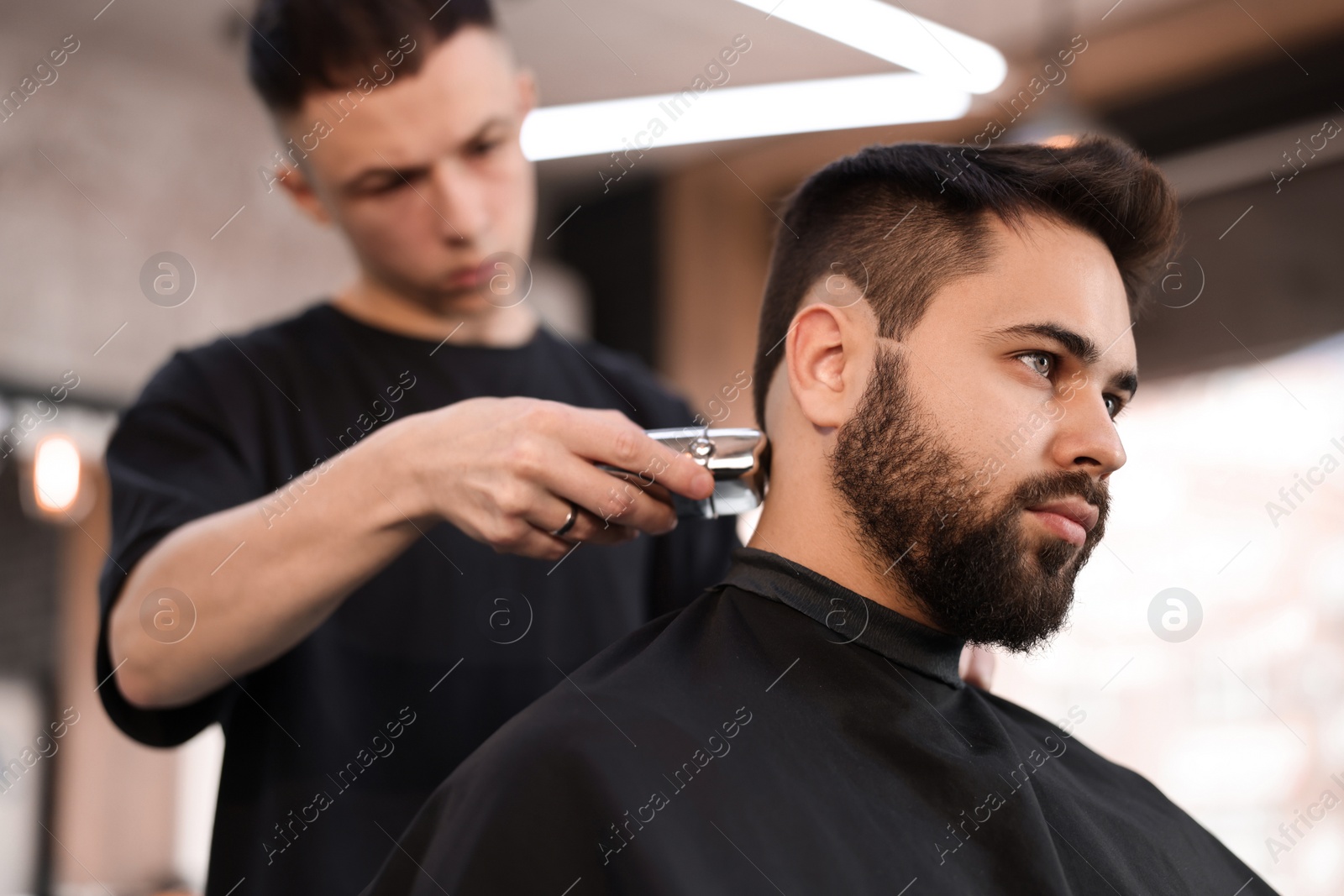 Photo of Professional hairdresser working with client in barbershop