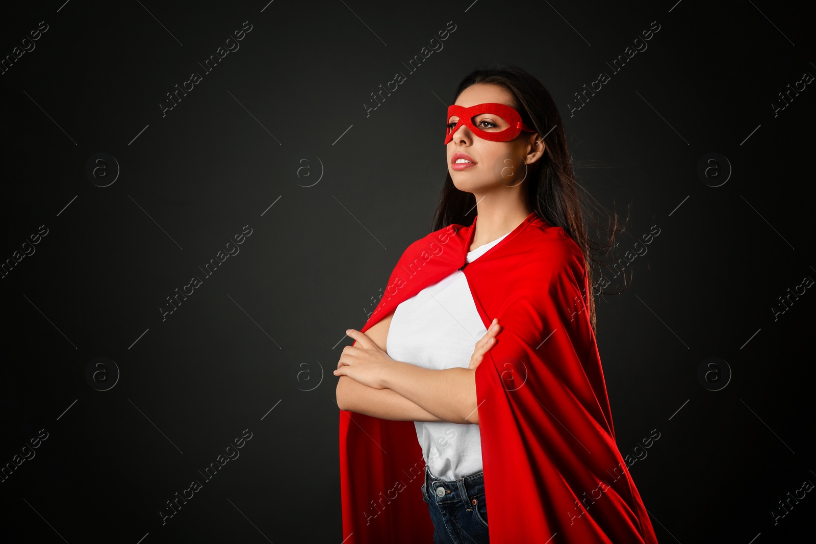 Photo of Confident young woman wearing superhero cape and mask on grey background, space for text
