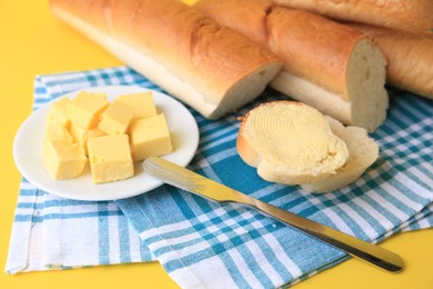 Photo of Cut baguette with fresh butter on yellow background