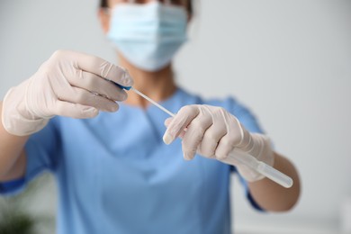 Photo of Doctor holding buccal cotton swab and tube for DNA test in clinic, closeup