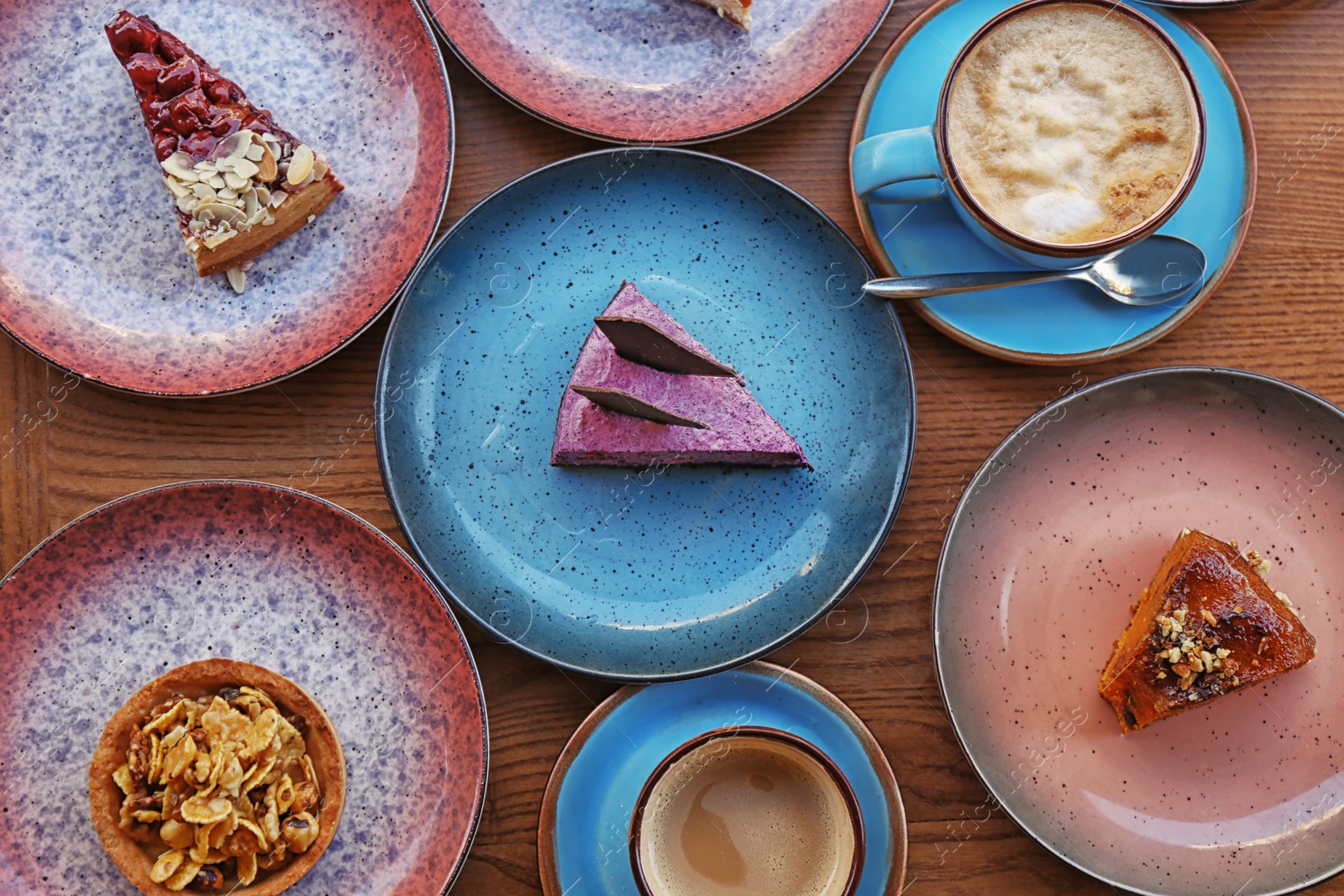 Photo of Plates with different cakes and aromatic coffee on wooden table, top view