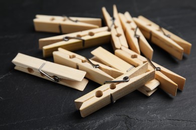 Photo of Wooden clothespins on black slate table, closeup