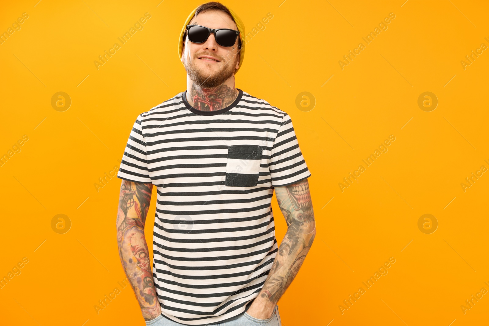 Photo of Handsome hipster man wearing stylish sunglasses on orange background. Space for text