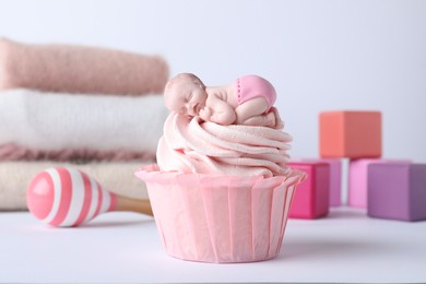 Beautifully decorated baby shower cupcake for girl with pink cream and topper on light background, closeup