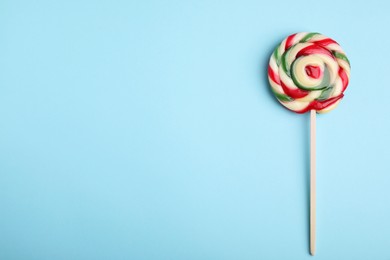 Photo of Colorful lollipop on light blue background, top view. Space for text