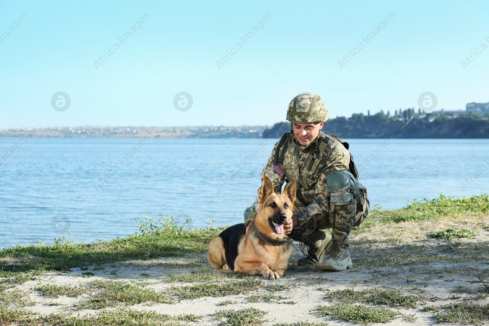 Photo of Man in military uniform with German shepherd dog near river, space for text