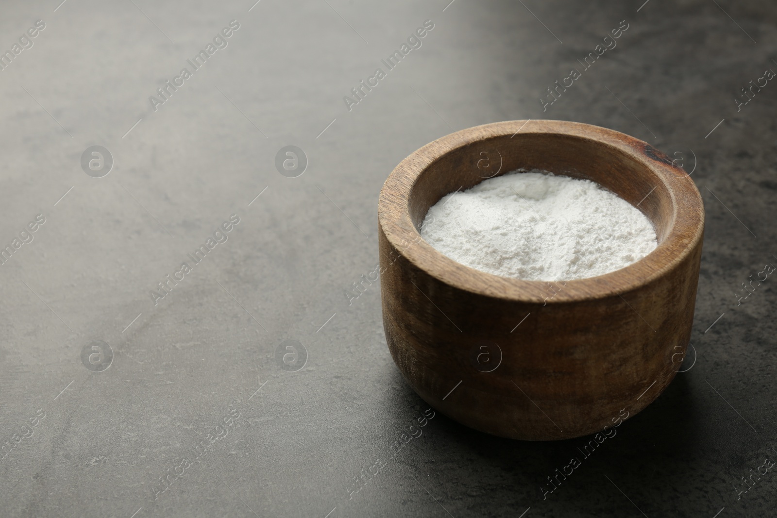 Photo of Baking powder in bowl on grey textured table, space for text