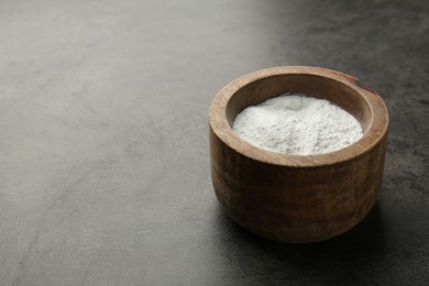 Photo of Baking powder in bowl on grey textured table, space for text