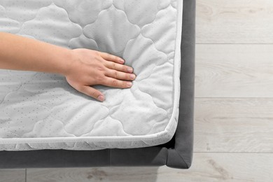 Woman touching soft light green mattress on bed, top view