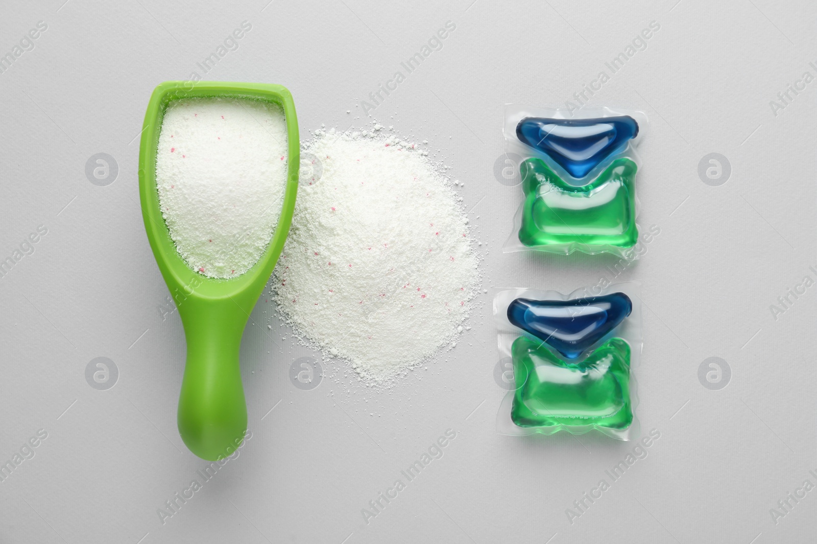 Photo of Laundry capsules and detergent powder on light grey background, flat lay