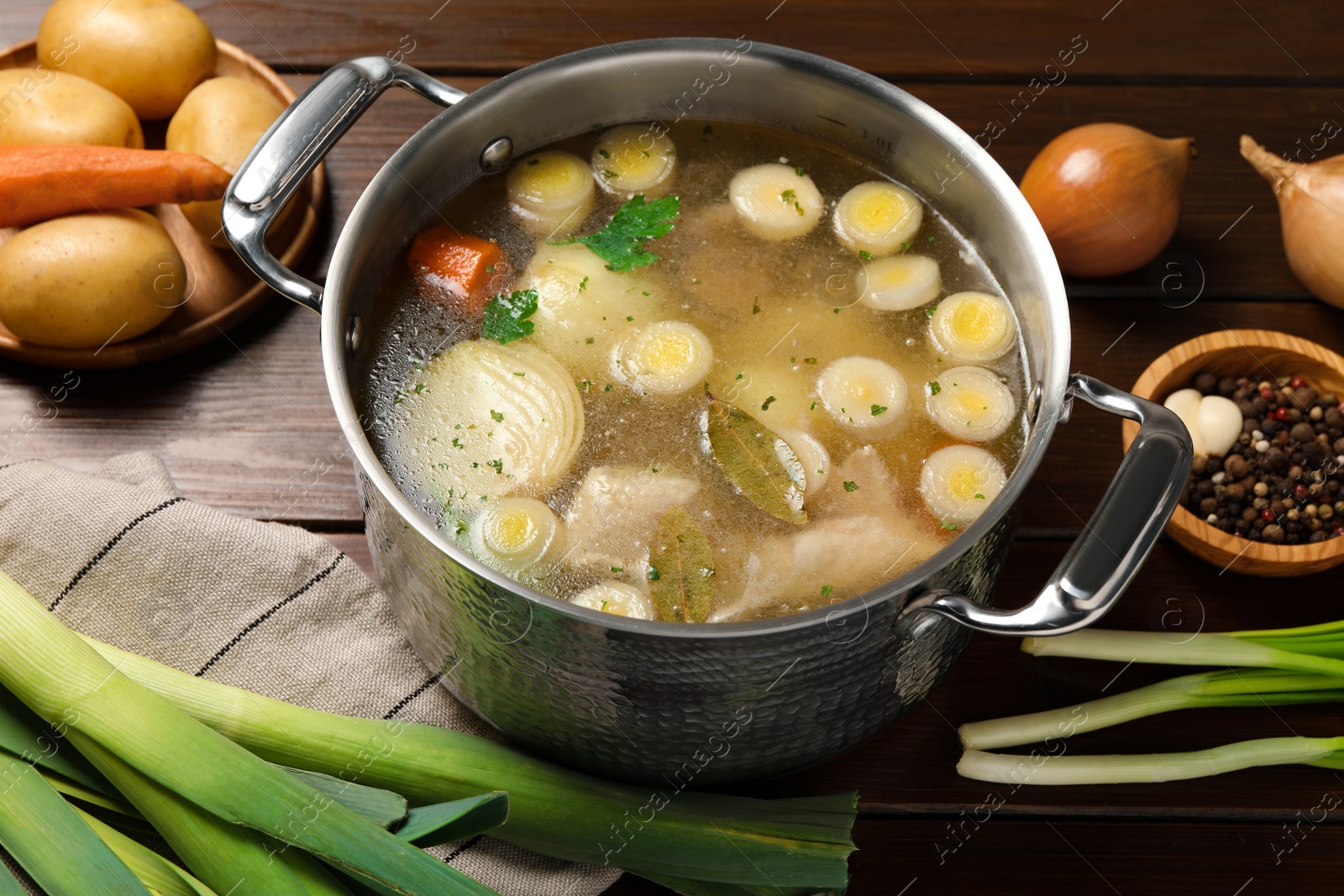 Photo of Pot with tasty bouillon and different ingredients on wooden table