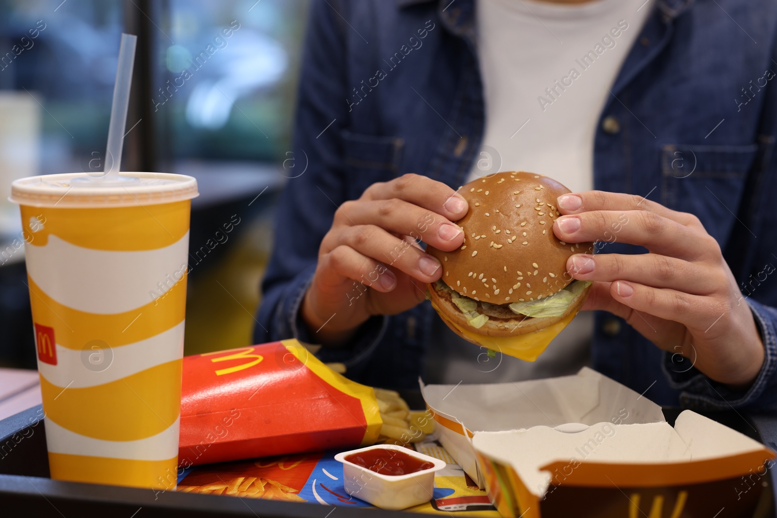 Photo of Lviv, Ukraine - October 9, 2023: Woman with McDonald's menu at table in restaurant, closeup