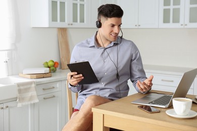 Businessman in shirt and underwear having videocall on laptop at home