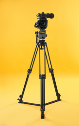 Modern professional video camera on yellow background