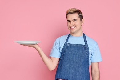 Photo of Portrait of happy confectioner holding empty plate on pink background