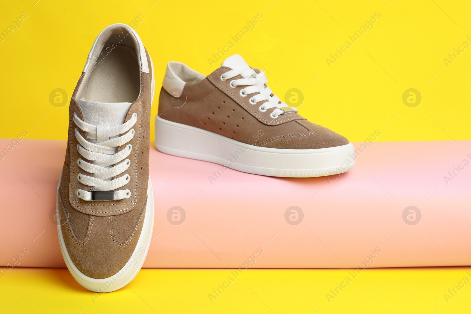 Photo of Pair of stylish brown shoes on yellow background