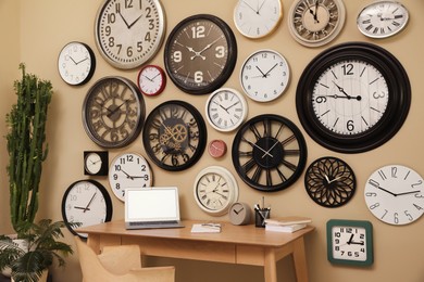 Stylish room interior with collection of wall clocks and workplace