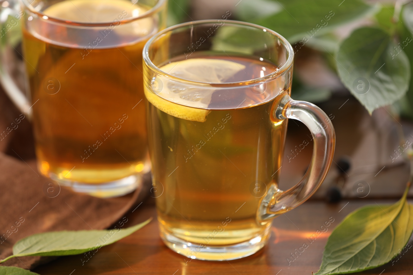 Photo of Cups of tasty iced tea with lemon on wooden table, closeup