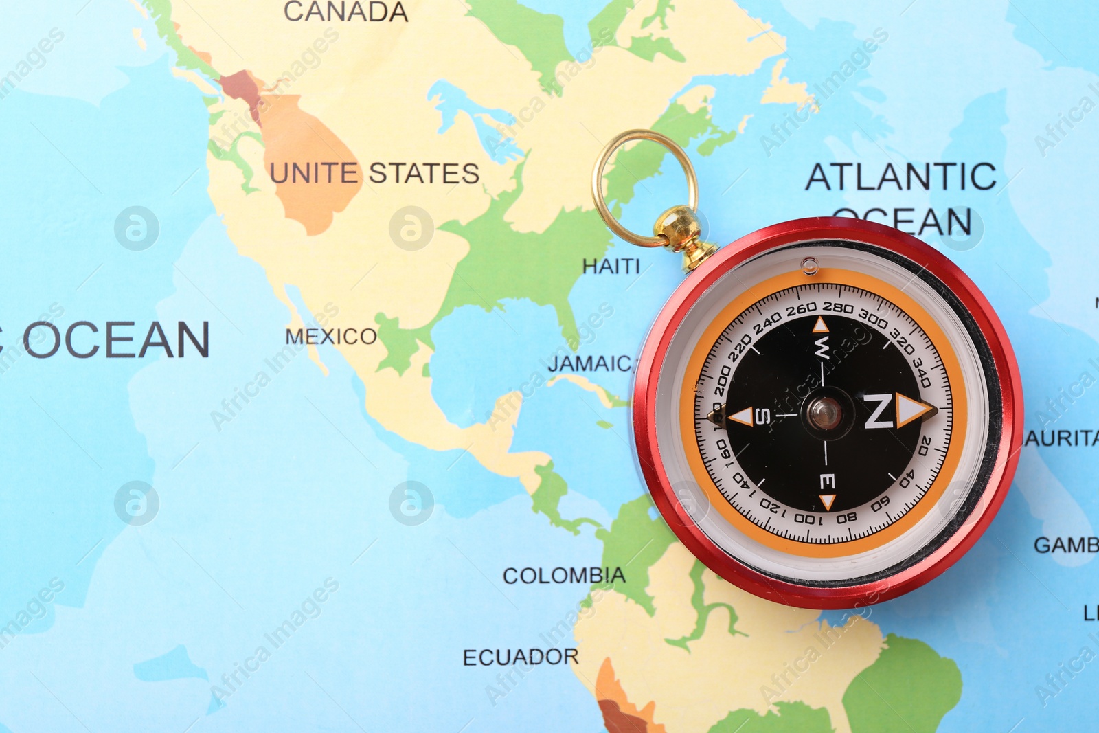 Photo of Compass on world map, top view. Navigation equipment