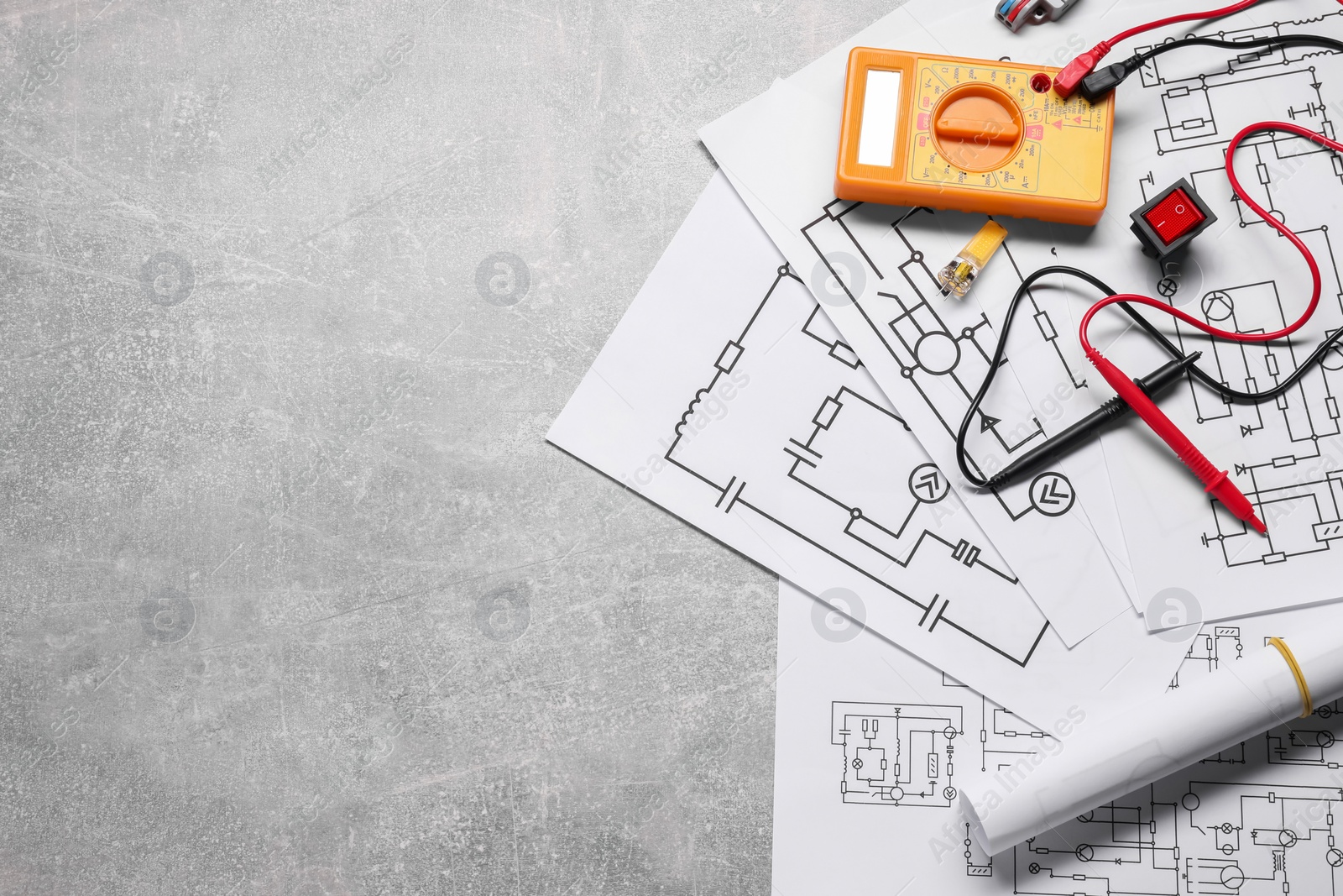 Photo of Flat lay composition with wiring diagrams and digital multimeter on grey table, space for text