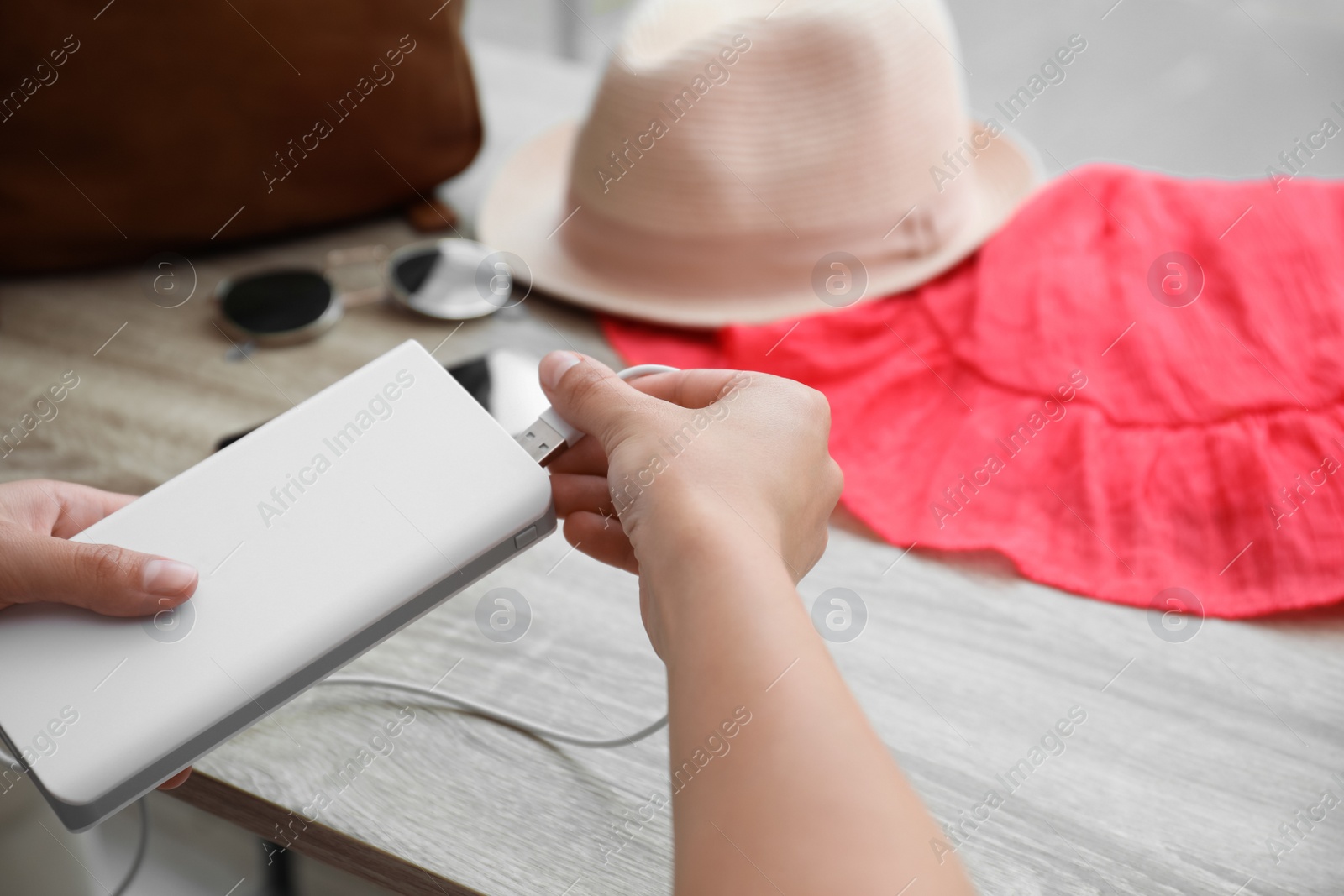 Photo of Woman charging mobile phone with power bank while getting ready for travel, closeup